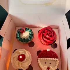 My special Christmas-themed cupcakes. This box of four includes designs like a Santa hat, a wreath, a red rose, and a candle, all hand-piped with buttercream to bring some festive cheer.
