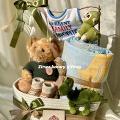 This hamper is for the 'Current Family Favorite'. It includes a cool teddy bear, dinosaur toys, and a cozy blanket, all in a handsome green and brown color scheme.