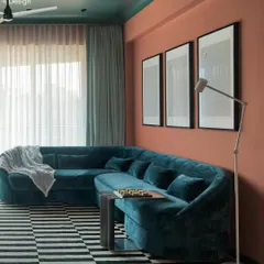The living room of Project 704 is a study in contrasts. A plush, deep teal L-shaped couch sits against a terracotta wall, while a graphic black-and-white striped carpet from Jaipur Rugs adds a fun, modern element.