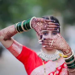A creative pose by the bride, framing her face with her beautifully stained hands. The dark color of the mehandi stands out, highlighting the intricate details of the design.