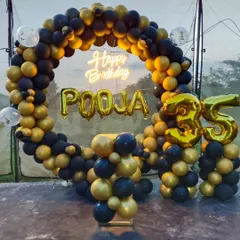 I design sophisticated decorations for milestone birthdays, like this stylish setup for a 35th celebration. It features a full ring backdrop covered in classic black and metallic gold balloons. To make it personal, I add large gold foil balloons for the name and age, along with a bright neon sign.