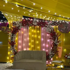 A closer look at the seating area for the Haldi ceremony. The backdrop features a circular floral arch against pink and yellow drapes, providing a beautiful spot for photos.