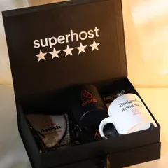 This top-down shot of the open Airbnb hamper highlights the arrangement of each custom item, including two different branded mugs and a personalized award.