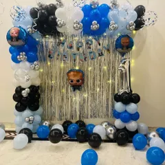 A simple yet fun Boss Baby theme decoration for a home celebration. This setup features a balloon arch over a silver fringe curtain and character foil balloons.