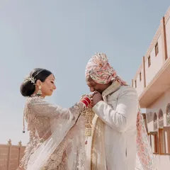 A tender moment between the bride and groom, showcasing a blend of tradition and romance. This shot highlights the intricate details of their outfits against the rustic palace walls.
