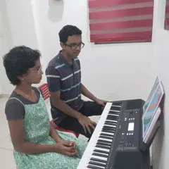 A keyboard student learning alongside her instructor. This side-by-side guidance helps in correcting techniques in real-time.