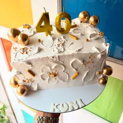 A stylish way to celebrate 40! This is a half-cake, shaped to be part of a larger number design, decorated in white and gold.
