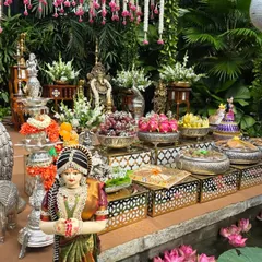 A close-up of the offering table at the outdoor ceremony, featuring silver props, traditional dolls, and a small pond with lotus flowers.