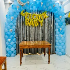 A 'Welcome Baby' decoration with a blue balloon arch over a silver tinsel curtain, perfect for a photo corner.