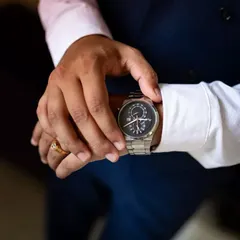 It's time. A classic groom's detail shot, focusing on his hands as he adjusts his watch before the ceremony.
