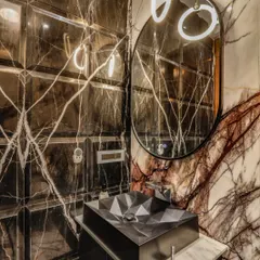 In this powder room, we used dramatic, book-matched marble and beveled wall tiles to create an immersive experience. The geometric basin and modern lighting add a contemporary edge, proving that even small spaces can make a powerful statement.