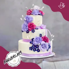 A spectacular three-tier floral cake designed for a special anniversary in GK2. The vibrant purple and pink sugar flowers create a stunning cascade, making it a truly memorable centerpiece.