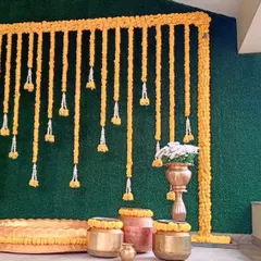 This Haldi decor was set up on a home balcony, transforming the space with a vibrant marigold frame against a green backdrop for a fresh, festive look.