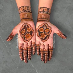 This design features a large, framed floral motif in the center of the palm. The fingers are adorned with a simple leaf pattern, drawing all the attention to the intricate flower work.