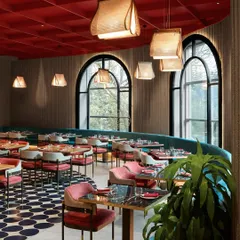 A long, curved teal booth follows the line of the large arched windows, maximizing seating while offering beautiful views. The custom pendant lights add a soft, organic touch to the vibrant space.