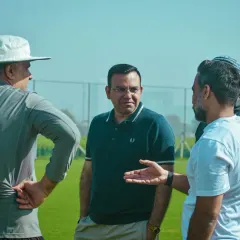 A group of coaches and parents discussing tactics and sharing insights during a break in play.