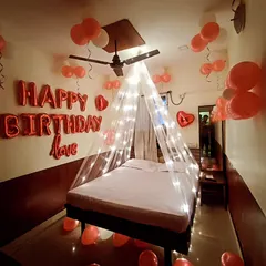 A classic red and white themed birthday room decoration. This setup includes "Happy Birthday love" foil balloons on the wall and a light-up canopy over the bed for a cozy and celebratory feel.