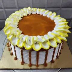 My butterscotch cake is a sweet and creamy treat. It features a smooth caramel topping, a border of yellow and white frosted petals, and a delicious caramel drip along the sides.
