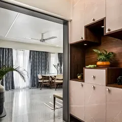 This entryway features a custom-built storage unit with a unique step design. The combination of closed cabinets and open, lit niches provides a practical and stylish solution for shoes and display items.
