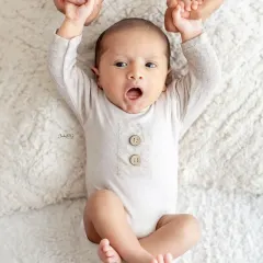 Look at that surprised expression. This awake newborn is holding onto his parents' hands, creating a beautiful and connected portrait.