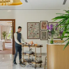 The banquet pre-function area at the DLF Club, where a fluted gold-toned bar and brass bar cart add sophistication. The space is designed to be warm and inviting, perfect for welcoming guests to an event.