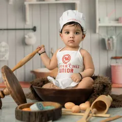 A portrait of our "Master Chef Junior" ready for culinary action. Themed shoots like this are perfect for sitter sessions, capturing a baby's steady posture and curious gaze.