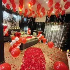We transform any room into a romantic paradise. This birthday surprise features a dramatic rose petal walkway, hundreds of red and white balloons, and a glowing neon sign, creating an unforgettable grand gesture.
