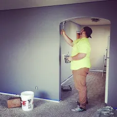 A painter carefully "cutting in" along the edge of an arched doorway. This precision work is crucial for achieving the sharp, clean lines that define a professional paint job.