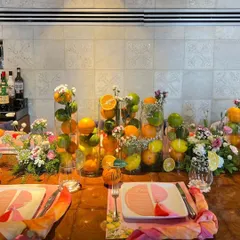 This summer birthday tablescape is bursting with freshness, using tall glass vases filled with whole lemons, limes, and oranges, interspersed with delicate floral bouquets.