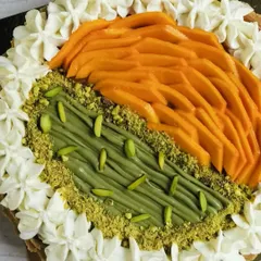 This close-up highlights the textures of the fresh mango, creamy pistachio spread, and the surrounding whipped cream topping.