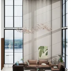 A stunning view of a double-height living space overlooking a lake, featuring a custom rod chandelier and floor-to-ceiling windows that flood the room with natural light.