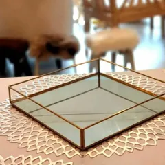 This square glass tray with a gold metal frame is a perfect example of modern elegance. It's a versatile piece that can be used to display dry fruits, sweets, or other small gifts within a larger hamper.