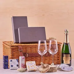 A luxurious wedding hamper featuring a wicker picnic basket, a bottle of Chandon, two wine glasses, and an assortment of elegant keepsakes and treats.