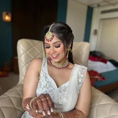 A beautiful party makeup look in a white lehenga with pink accents. The smokey eye and braided ponytail create a style that is both trendy and timeless.