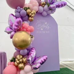 For a touch of modern elegance, we designed this "A Little Butterfly is on the way" theme. It features a custom lavender arched backdrop, adorned with an organic balloon garland in shades of purple, pink, and gold, and accented with large, shimmering butterfly foils.