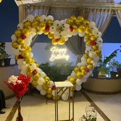 An impressive heart-shaped balloon arch made of gold and white balloons, accented with red roses. This arch creates a perfect photo backdrop for birthdays, anniversaries, or proposals.