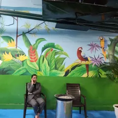 A closer look at the parrot illustrations within the Leela Hotel jungle mural. The bright colors of the birds stand out against the lush green foliage.