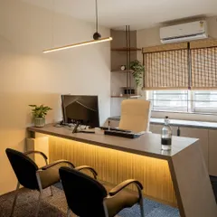 A private cabin designed for focused work, featuring a sleek, modern desk with integrated lighting. Natural textures like the bamboo blinds and a touch of greenery create a calm and productive atmosphere.