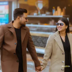 A close-up of a couple holding hands and smiling as they walk, their stylish coats perfect for a chic, urban pre-wedding shoot.