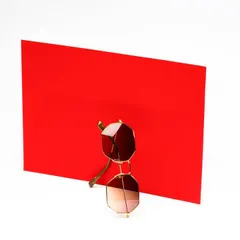 A minimalist and conceptual shot of sunglasses interacting with a bold red card. This artistic approach creates a memorable image that is more than just a standard product photo.