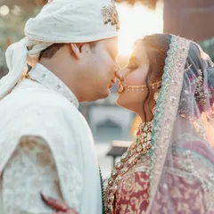 A stunning golden hour portrait just before the wedding. The warm sunlight creates a beautiful flare as they share an intimate moment, highlighting the intricate details of their traditional wedding attire.