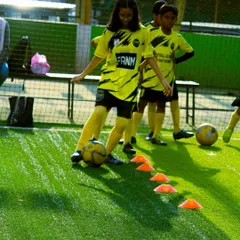 A young girl practices her dribbling through a cone drill, showcasing her focus and developing skill.