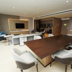 A wide shot capturing the dining area, living room, and a glimpse into the kitchenette, providing a comprehensive view of the suite's open-concept design.
