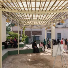 Women and children gather at the Basera Community Plaza. The design's openness and visibility from the street were crucial to making it an accessible and welcoming space for community discourse and grassroots activities.