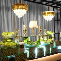 An artfully arranged salad bar under elegant chandeliers. We use multi-level displays and mirrored surfaces to create a sense of depth and luxury, ensuring even the simplest dishes are presented with extraordinary flair.