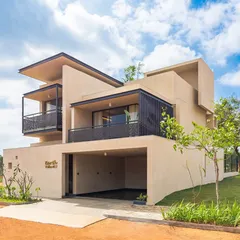 The exterior of an "Earth Villa" at Svamitva Terravana. The design uses a composition of simple, stacked volumes with mud plaster finishing, creating a form that is both modern and deeply connected to the earth.