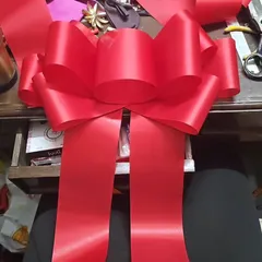 A behind-the-scenes look at the making of a giant celebration bow. Each one is crafted by hand from wide satin ribbon to create that perfect, voluminous shape, ready to adorn a new car, a storefront, or a huge gift.