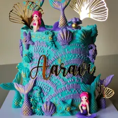 An underwater dream, this mermaid-themed cake is covered in detailed buttercream textures that mimic coral and waves. Shimmering mermaid tails, seashells, and gold accents complete this magical creation.