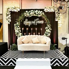 A chic and classic seating area for a Sangeet night. I used a black and white chevron pattern for the stage floor, a dark backdrop to make the white floral arch pop, and a custom "Always and Forever" neon sign. The elegant beige sofa completes this glamorous setup.