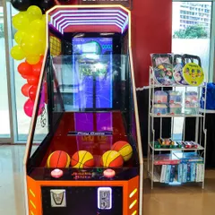 An arcade basketball machine set up for a Deadpool-themed party, complete with themed branding and prizes nearby.